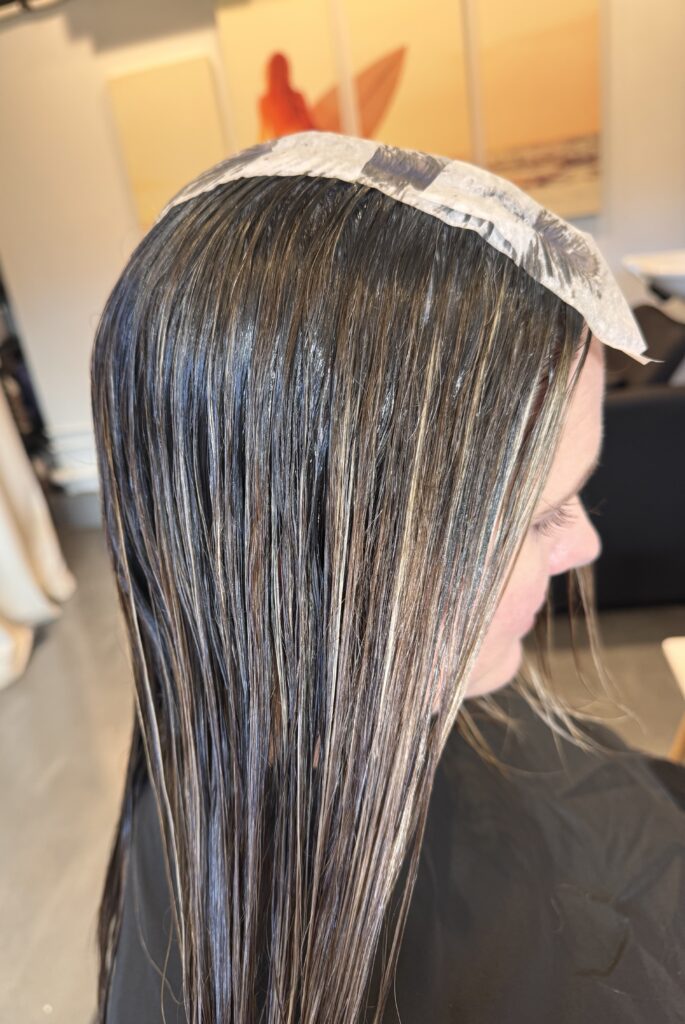stylist doing a root shadow, root tap and root melt